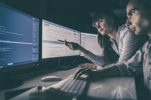 A woman sitting at a desk with multiple computer screens