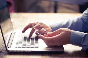 A person holding a transparent lock over a laptop